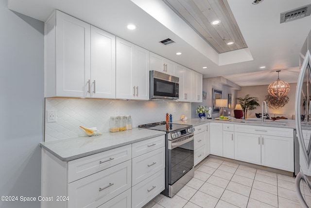 kitchen with tasteful backsplash, appliances with stainless steel finishes, light tile patterned flooring, and white cabinets