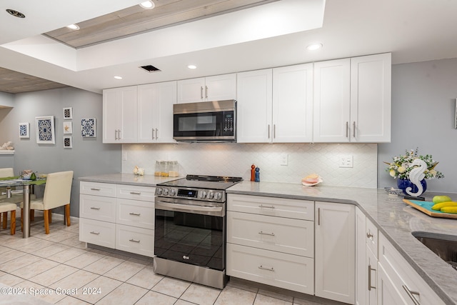 kitchen with white cabinetry, light stone countertops, light tile patterned flooring, backsplash, and stainless steel appliances