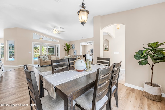 dining space with ceiling fan, light hardwood / wood-style flooring, and vaulted ceiling