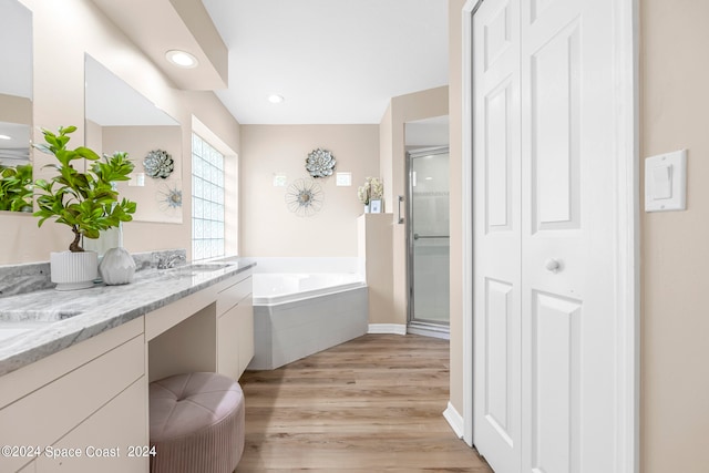 bathroom with dual bowl vanity, hardwood / wood-style floors, and separate shower and tub