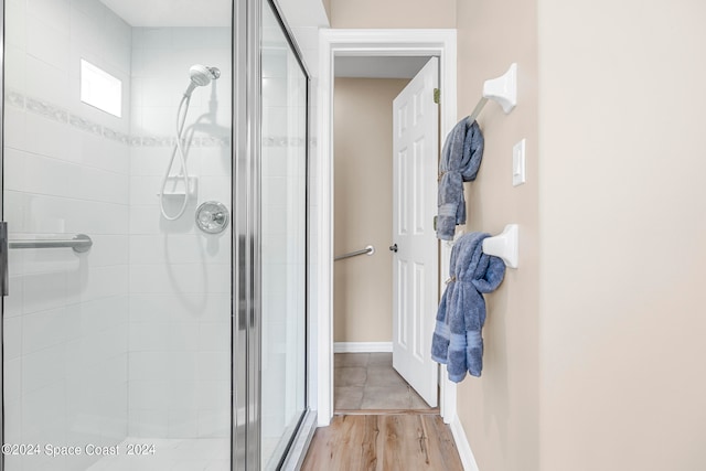 bathroom with a shower with door and hardwood / wood-style flooring