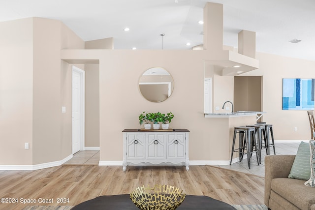 living room featuring lofted ceiling, sink, and light hardwood / wood-style flooring