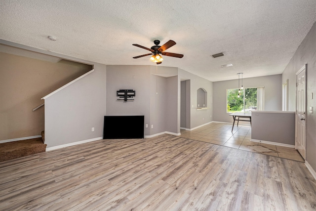 unfurnished living room featuring ceiling fan, light hardwood / wood-style flooring, and a textured ceiling