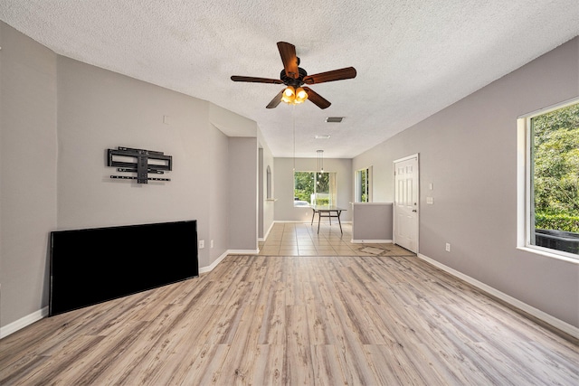 interior space featuring ceiling fan, light tile patterned floors, and a textured ceiling