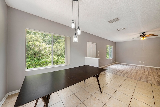 unfurnished dining area with ceiling fan, a textured ceiling, and light tile patterned floors