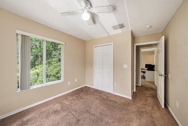 unfurnished bedroom with ceiling fan, carpet flooring, a textured ceiling, and a closet