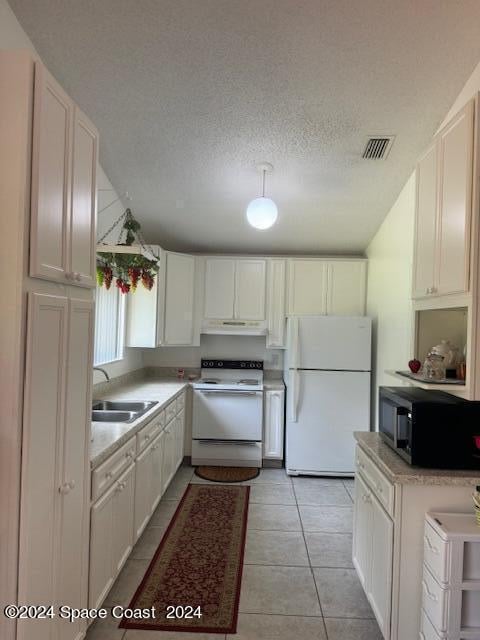 kitchen featuring a textured ceiling, white appliances, sink, light tile patterned floors, and white cabinetry