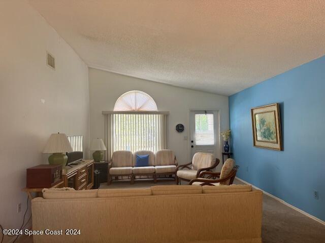 unfurnished living room featuring carpet flooring, lofted ceiling, and a textured ceiling