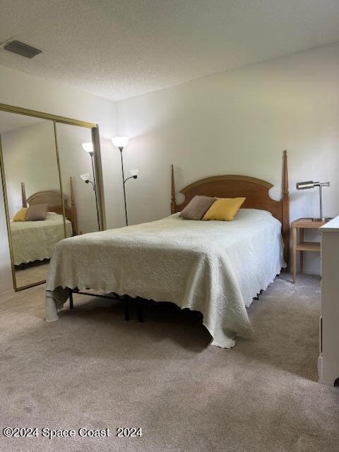 bedroom with a closet, carpet, and a textured ceiling