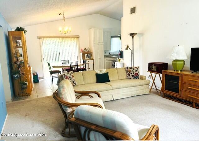 living room with a textured ceiling, light colored carpet, vaulted ceiling, and an inviting chandelier