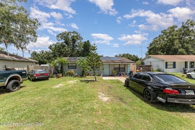 view of front of house featuring solar panels and a front lawn