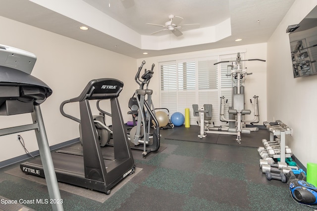 exercise room featuring ceiling fan and a tray ceiling