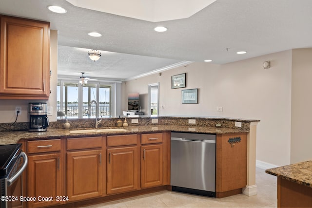 kitchen featuring sink, appliances with stainless steel finishes, dark stone countertops, a textured ceiling, and kitchen peninsula