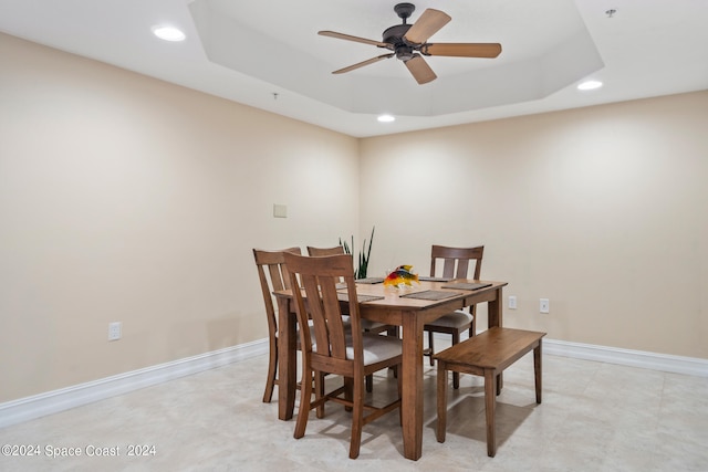 dining space featuring ceiling fan and a tray ceiling