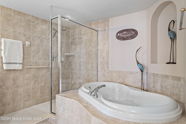 bathroom featuring separate shower and tub and a textured ceiling