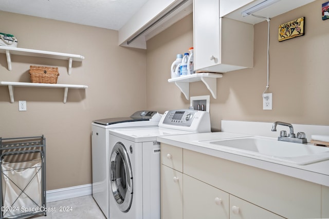 washroom with sink, light tile patterned floors, cabinets, and washing machine and clothes dryer