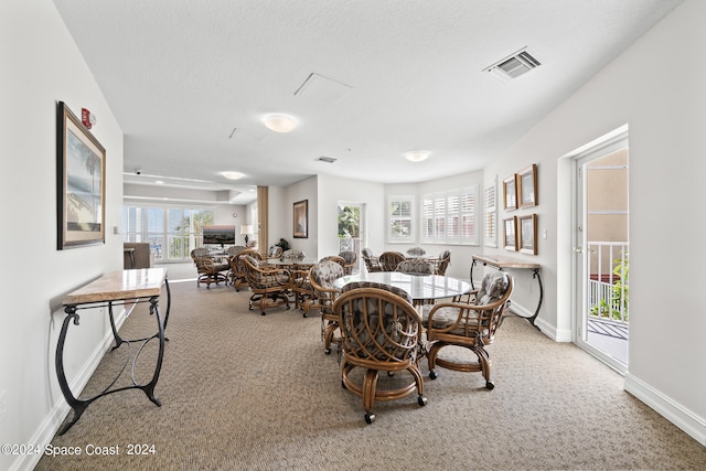 carpeted dining room featuring a textured ceiling