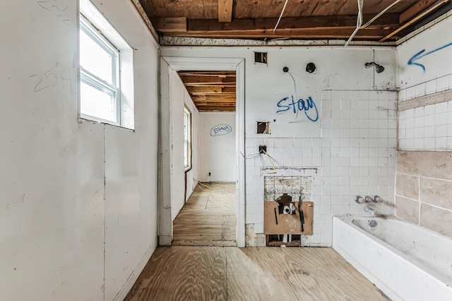 bathroom with wood finished floors and a bath