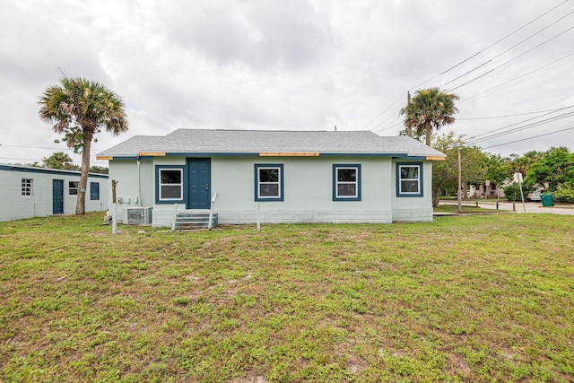 rear view of house with entry steps, central AC, and a yard