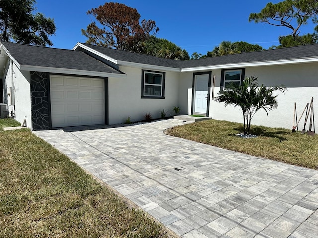 ranch-style home with a garage, cooling unit, and a front yard