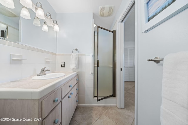 bathroom with decorative backsplash, tile patterned flooring, an enclosed shower, vanity, and tile walls