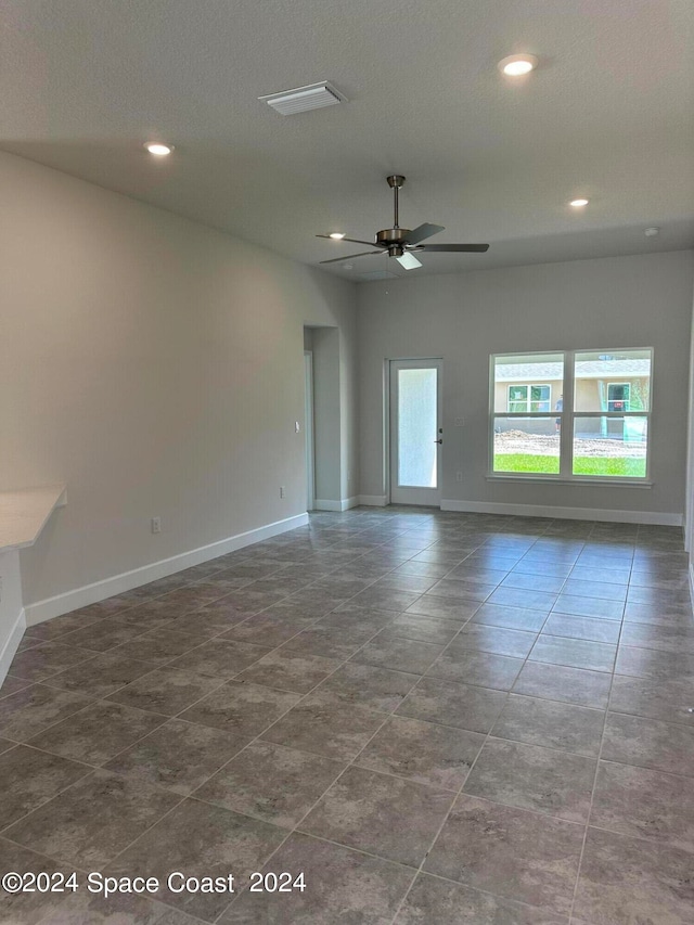 empty room with ceiling fan and a textured ceiling