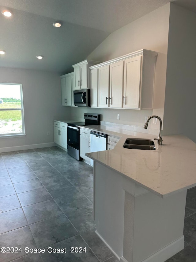 kitchen with appliances with stainless steel finishes, light stone countertops, sink, lofted ceiling, and kitchen peninsula