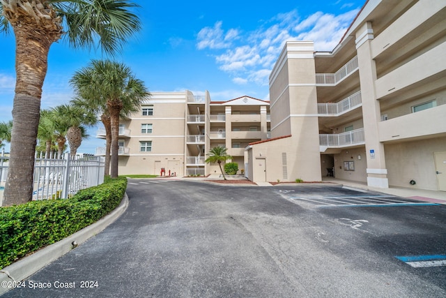 view of building exterior featuring uncovered parking and fence