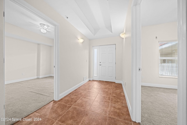 carpeted foyer entrance featuring tile patterned flooring, baseboards, and a ceiling fan