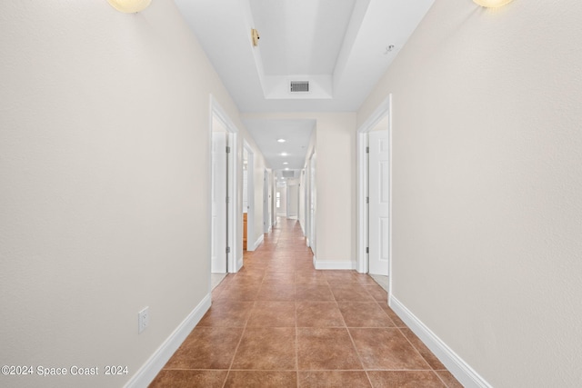 corridor with visible vents, baseboards, and tile patterned floors