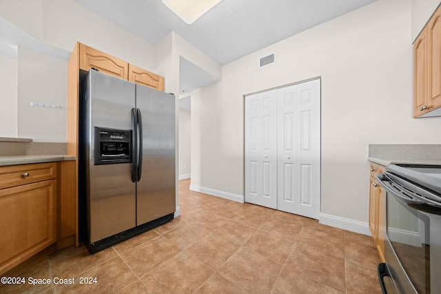 kitchen featuring electric stove, light countertops, visible vents, stainless steel fridge, and baseboards