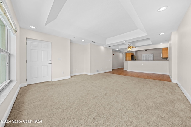 unfurnished living room featuring carpet floors, baseboards, a tray ceiling, and recessed lighting