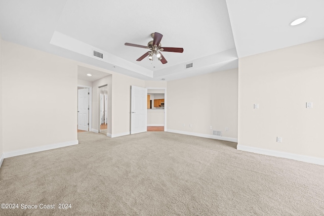 carpeted spare room featuring a tray ceiling and ceiling fan