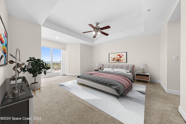 carpeted bedroom featuring access to exterior, baseboards, a tray ceiling, and a ceiling fan