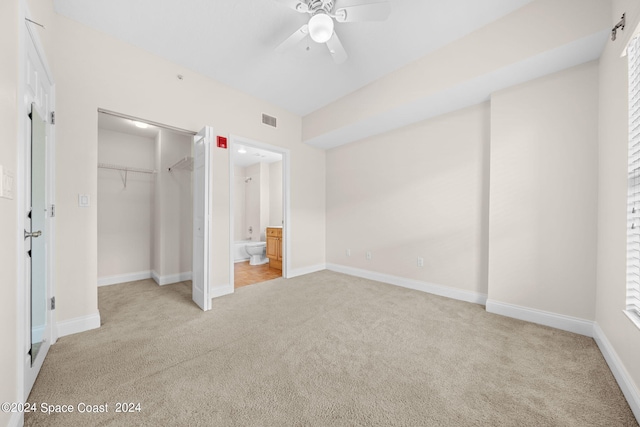 unfurnished bedroom with light colored carpet, ceiling fan, ensuite bath, and a closet