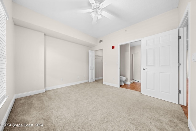 unfurnished bedroom with light carpet, ensuite bathroom, and ceiling fan