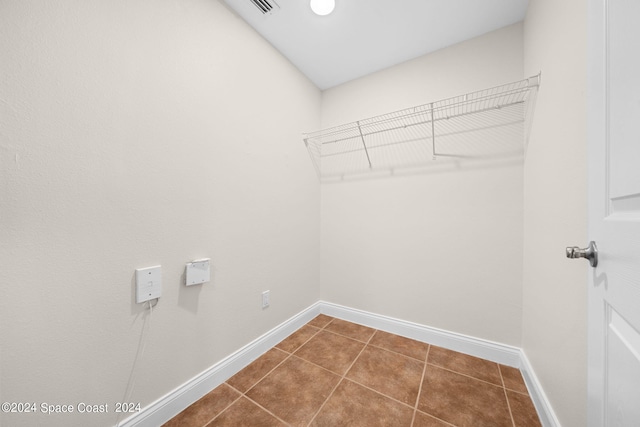 clothes washing area featuring dark tile patterned flooring, visible vents, and baseboards