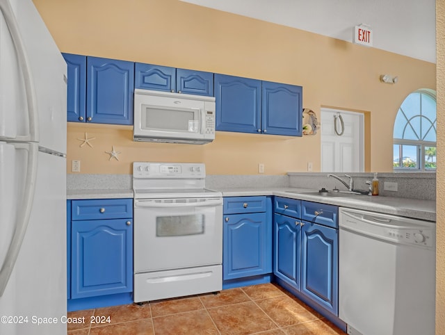 kitchen featuring light tile patterned floors, blue cabinetry, white appliances, and a sink