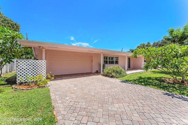 ranch-style house featuring brick siding, a front lawn, fence, decorative driveway, and an attached garage