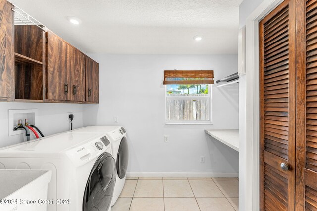 laundry area featuring cabinets, independent washer and dryer, sink, light tile patterned floors, and a textured ceiling