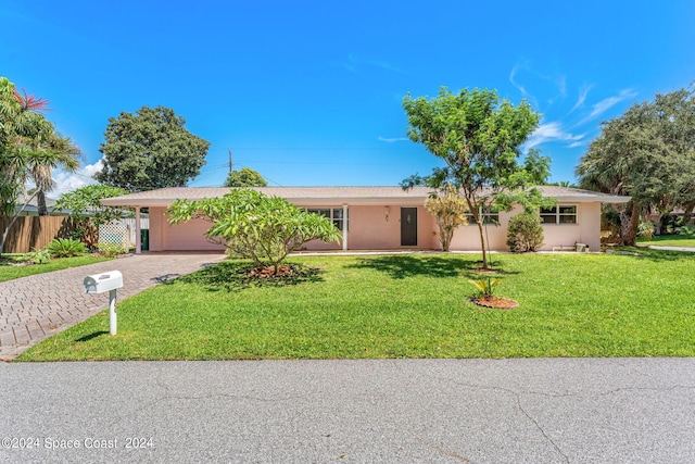 ranch-style home with a front yard, fence, stucco siding, a garage, and decorative driveway