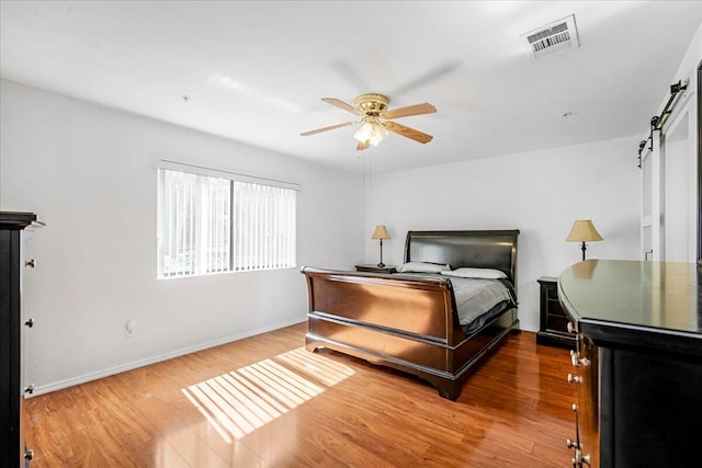 bedroom featuring ceiling fan, hardwood / wood-style floors, and a barn door