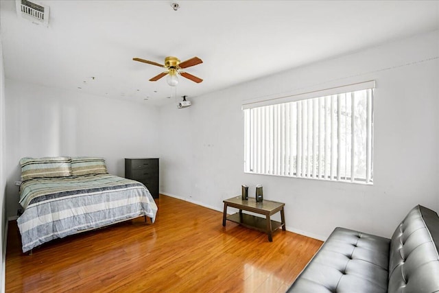 bedroom featuring ceiling fan, hardwood / wood-style floors, and multiple windows