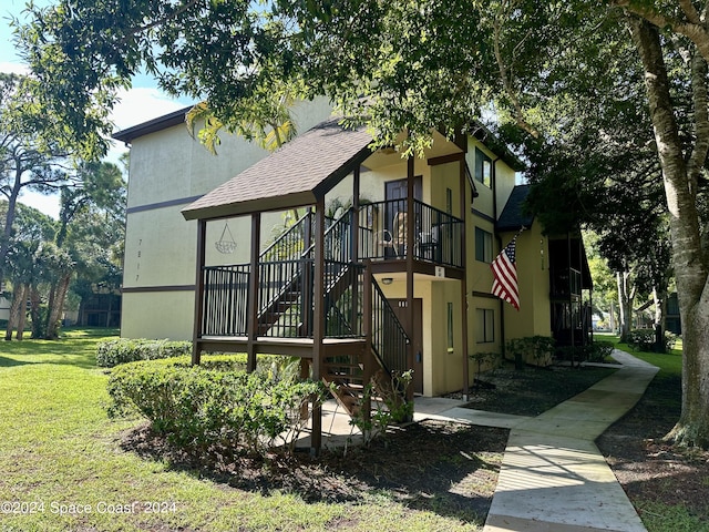 7817 Maplewood Dr Unit 601, Melbourne, FL 32904 - exterior space featuring stucco siding, a front yard, stairway, and roof with shingles