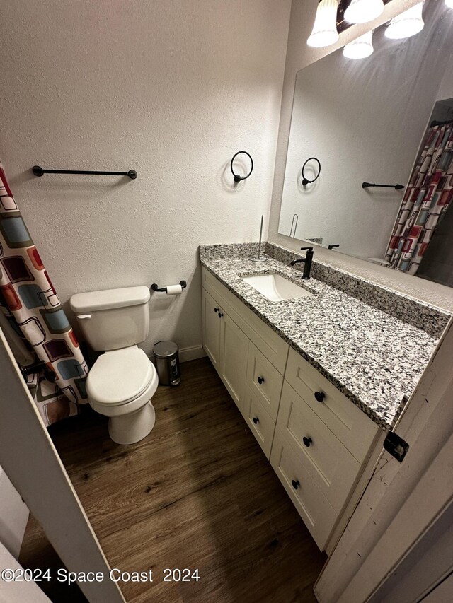 bathroom with hardwood / wood-style flooring, vanity, and toilet