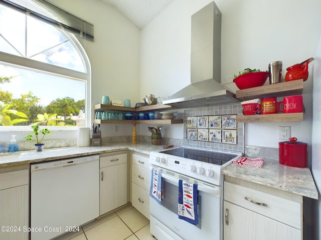 kitchen featuring light tile patterned floors, range hood, light stone counters, and white appliances