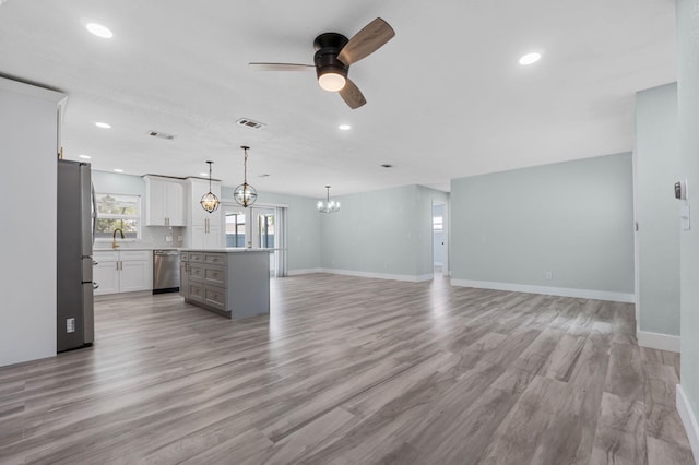 kitchen with light wood-type flooring, white cabinets, stainless steel appliances, and a center island