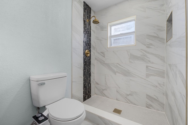 bathroom featuring toilet and a tile shower