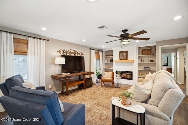 living room with a fireplace, ceiling fan, built in features, and hardwood / wood-style flooring