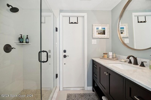 bathroom with a shower with door and vanity